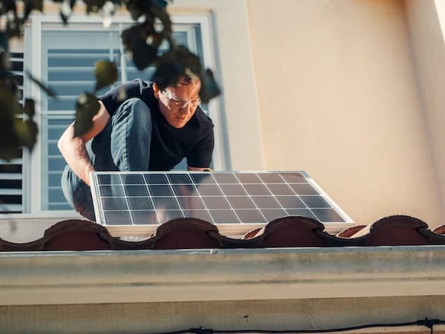 A man installing a solar panel on a roof.